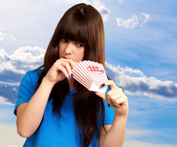 Girl looking through empty popcorn packet — Stock Photo, Image