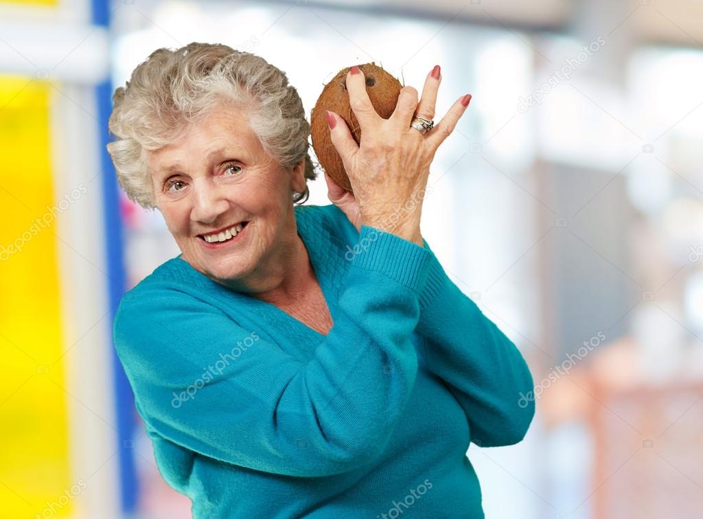 Senior happy woman holding coconut