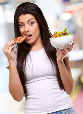 kadın bir parça pizza yemek ve salata kasesi holding