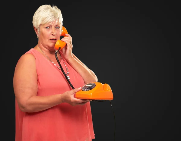 Retrato de uma mulher sênior segurando um telefone retro — Fotografia de Stock