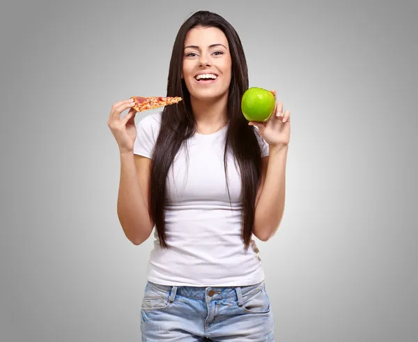 Mujer sosteniendo un pedazo de pizza y una manzana — Foto de Stock