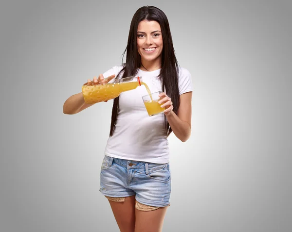 Porträt einer jungen Frau, die einen Orangensaft in ein Glas gießt — Stockfoto