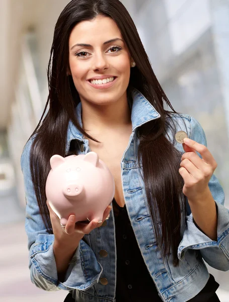 Портрет женщины, держащей монету и свинью — стоковое фото