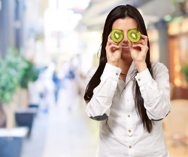 Chica joven sosteniendo rebanadas de kiwi —  Fotos de Stock