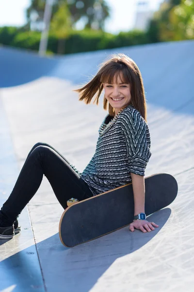 Felice donna seduta con skateboard — Foto Stock