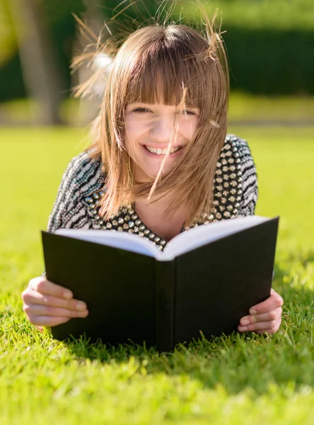 Счастливая женщина читает книгу в парке — стоковое фото