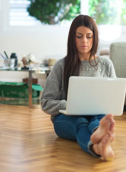 Jonge vrouw zittend op de vloer en met behulp van laptop — Stockfoto