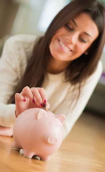 Ung kvinna att lägga mynt i piggybank — Stockfoto