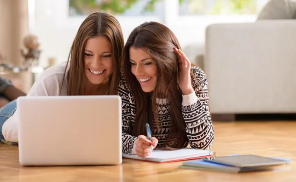ผู้หญิงสองคนมีความสุขมองไปที่แล็ปท็อป ภาพสต็อก