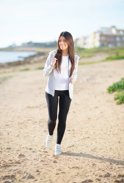 Junge Frau joggt am Strand — Stockfoto