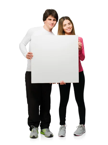 Feliz joven pareja sosteniendo placa en blanco — Foto de Stock