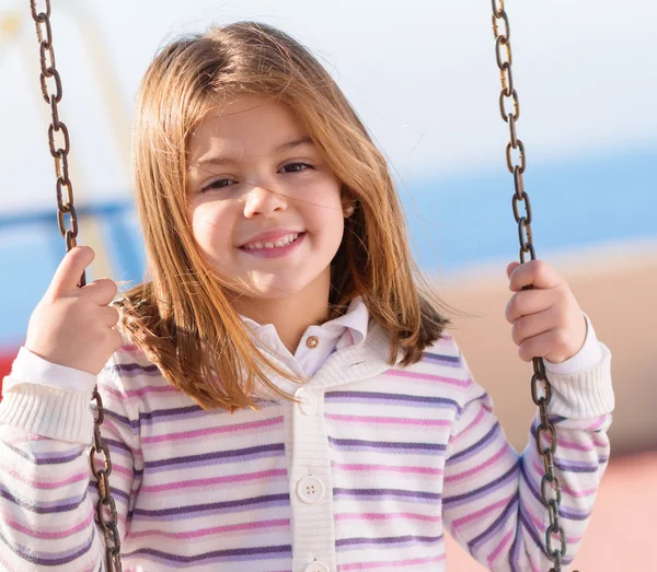 Small girl swinging in playground — Stock Photo, Image