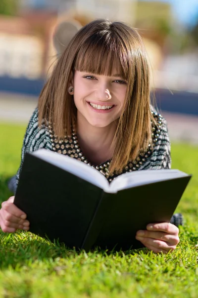 Mujer feliz leyendo libro en el parque — Foto de Stock