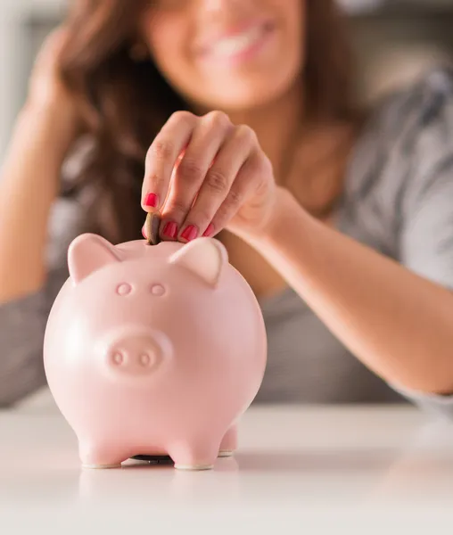 Kvinnan sätter mynt i Piggy Bank — Stockfoto