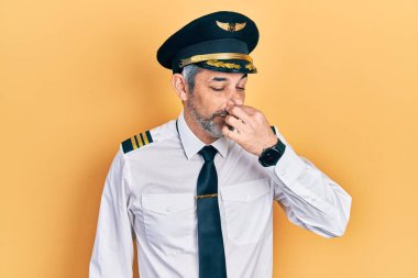 Gri saçlı, uçak pilotu üniforması giyen yakışıklı orta yaşlı bir adam. Kokuşmuş ve iğrenç bir koku alıyor. Dayanılmaz bir koku. Kötü kokuyor. 