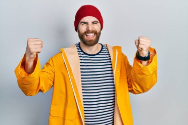 Sakallı, sarı yağmurluk giyen, kızgın ve kızgın beyaz bir adam öfkeyle bağırırken sinirli ve öfkeli yumruklar sallıyor. öfke ve agresif konsept. 