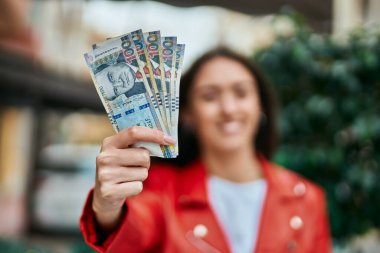 Genç İspanyol kadın gülümsüyor. Mutlu bir şekilde Peru banknotlarını şehirde tutuyor..