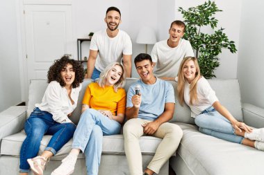 Bir grup genç arkadaş evde mikrofon kullanarak şarkı söylüyor..