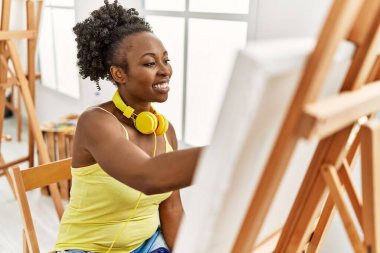Genç Afrikalı Amerikalı kadın sanat stüdyosunda kulaklık kullanıyor..