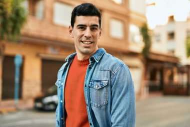 Genç İspanyol adam gülümseyerek şehirde mutlu mesut dikiliyor..