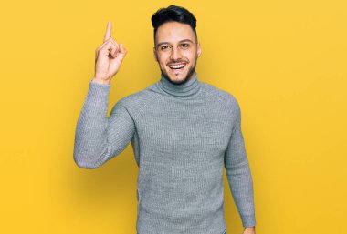 Gündelik giysiler giymiş genç bir Arap başarılı bir fikirle işaret ediyor. Heyecanlı ve mutlu. Bir numara.. 