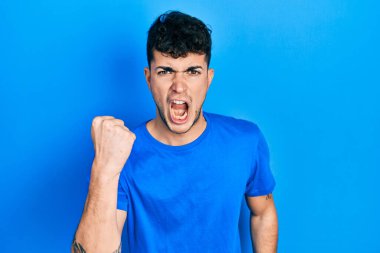 Latin asıllı genç adam öfkeyle bağırırken kızgın ve kızgın bir şekilde yumruk kaldırıyor. öfke ve agresif konsept. 