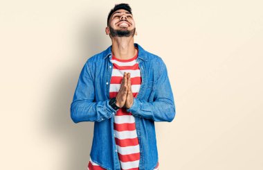 Sakallı, sıradan bir kot ceket giyen, elleri bağlı, yalvaran, dua eden, yüzünde umut ifadesi olan genç İspanyol bir adam çok duygusal ve endişeli. Yalvarıyor. 