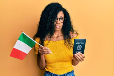 Orta yaşlı Afro-Amerikalı kadın elinde İtalyan bayrağı ve pasaport ve kafası karışık bir ifade tutuyordu. şüphe kavramı. 