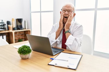 Ofiste çalışan son sınıf öğrencisi bilgisayar kullanıyor. Korkmuş ve şok olmuş, şaşırmış ve şaşırmış bir yüz ifadesi var. 