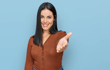 Genç İspanyol kadın günlük kıyafetler giyip gülümseyerek selamlaşma ve dostça tokalaşma sunuyor. başarılı iş. 