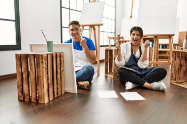 Sanat stüdyosundaki genç İspanyol çift gururla bağırıyor, zaferi kutluyor ve kollarını kaldırarak çok heyecanlanıyor. 