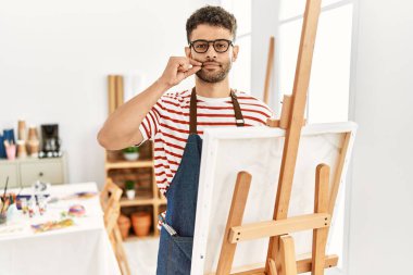 Sanat stüdyosundaki Arap genç adamın ağzı ve dudakları parmakları fermuar gibi kapalıydı. gizli ve sessiz, tabu konuşması 