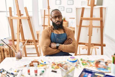 African american artist man at art studio skeptic and nervous, disapproving expression on face with crossed arms. negative person. 