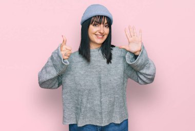 Şirin yün şapkalı genç İspanyol kadın gülümseyerek kendinden emin ve mutlu gülümserken altı numarayı işaret ediyor.. 