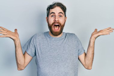 Gri bir tişört giyen beyaz bir adam çılgınlığı kutluyor ve kolları havada ve gözleri açık heyecanla haykırarak başarıyı kutluyor. Kazanan konsept 