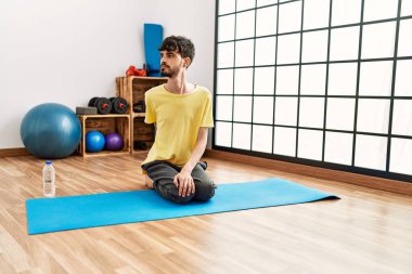 Spor merkezinde yoga eğitimi alırken gülümseyen İspanyol genç adam..