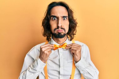 Hipster şık görünümlü, papyon takan komik yüzlü genç İspanyol adam. Ağzı havayla şişer, havayı yakalar.. 