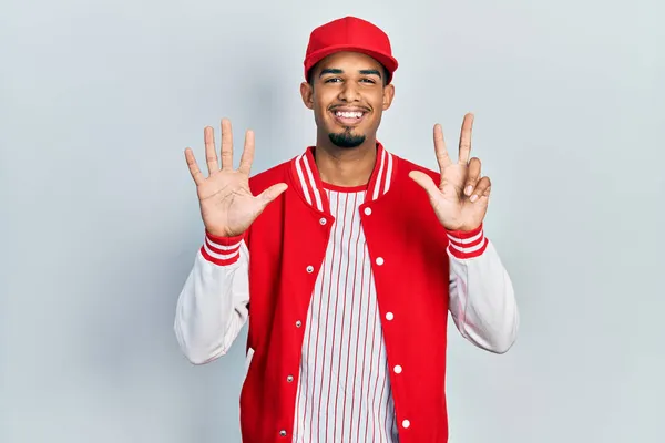 自信と幸せな笑顔ながら 若いアフリカ系アメリカ人の男は 野球の制服を着て指の数8で示すと指摘します — ストック写真