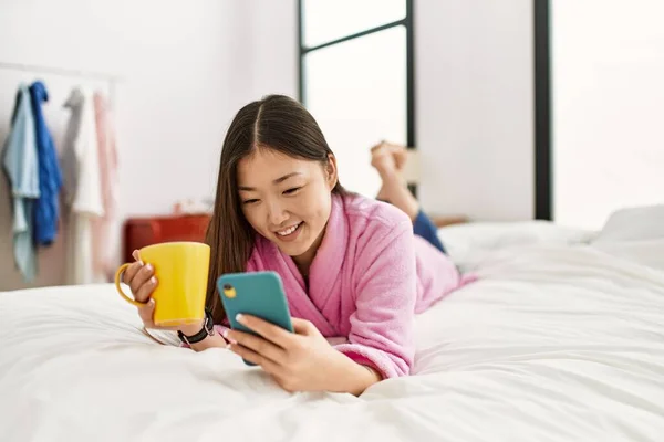 Молода Китайка Користуючись Смартфоном Ючи Каву Лежить Ліжку Спальні — стокове фото