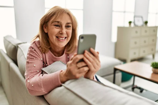 Středního Věku Blondýny Žena Pomocí Smartphone Sedí Pohovce Doma — Stock fotografie