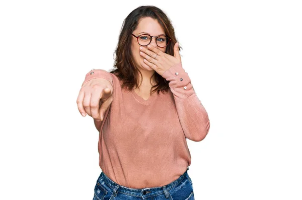 若いプラスサイズの女性はカジュアルな服やメガネを着てあなたを笑って 口の上に手でカメラに指を指して 恥の表情 — ストック写真