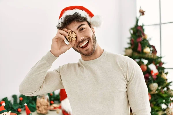 Mladý Hispánec Muž Nosí Vánoční Klobouk Drží Sušenky Přes Oko — Stock fotografie