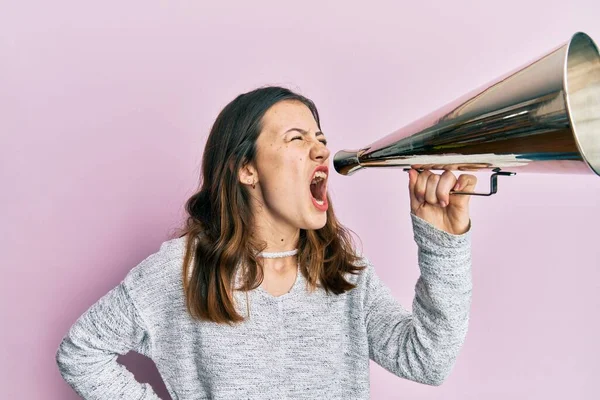 年轻的黑发女人在粉色孤立的背景下 通过老式扩音器大喊大叫 — 图库照片