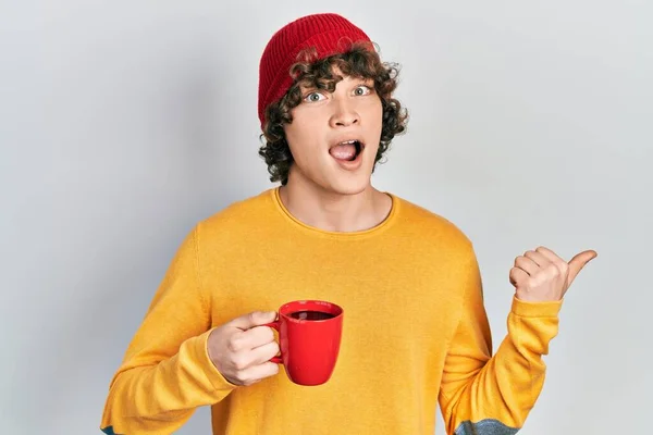 Jóképű Fiatalember Iszik Egy Csésze Kávét Mutatva Hüvelykujját Felfelé Mosolyogva — Stock Fotó