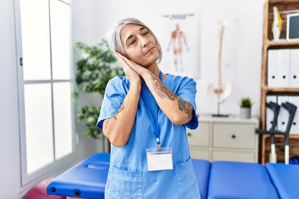 Medelålders Gråhårig Kvinna Klädd Sjukgymnast Uniform Läkarmottagningen Sover Trött Drömmer — Stockfoto