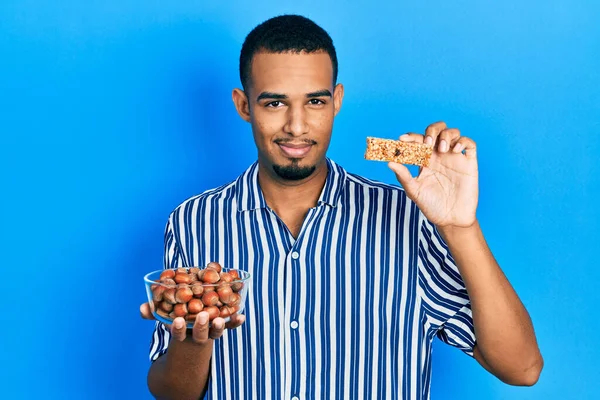 Hombre Afroamericano Joven Sosteniendo Avellanas Crudas Barra Cereales Relajado Con — Foto de Stock
