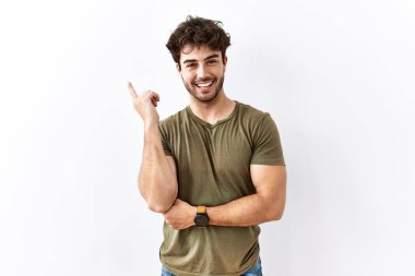 İzole edilmiş beyaz arka planda duran İspanyol bir adam. Yüzünde kocaman bir gülümseme var. Parmağıyla kameraya bakıyor.. 