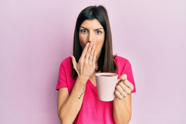Genç İspanyol kadın kızgın suratlı bir fincan kahve içiyor, negatif işaret baş parmakları aşağıda, reddedilme konsepti 