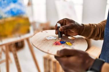 Palet sanat stüdyosunun rengini karıştıran Afrikalı Amerikalı sanatçı..