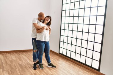 Genç İspanyol çift mutlu bir şekilde gülümsüyor ve boş yeni evlerinde sarılıyorlar..